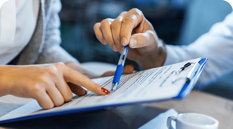 Two people collaborating over written notes with pen and finger.
