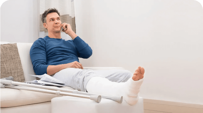 Man with a leg cast talking on the phone while resting.